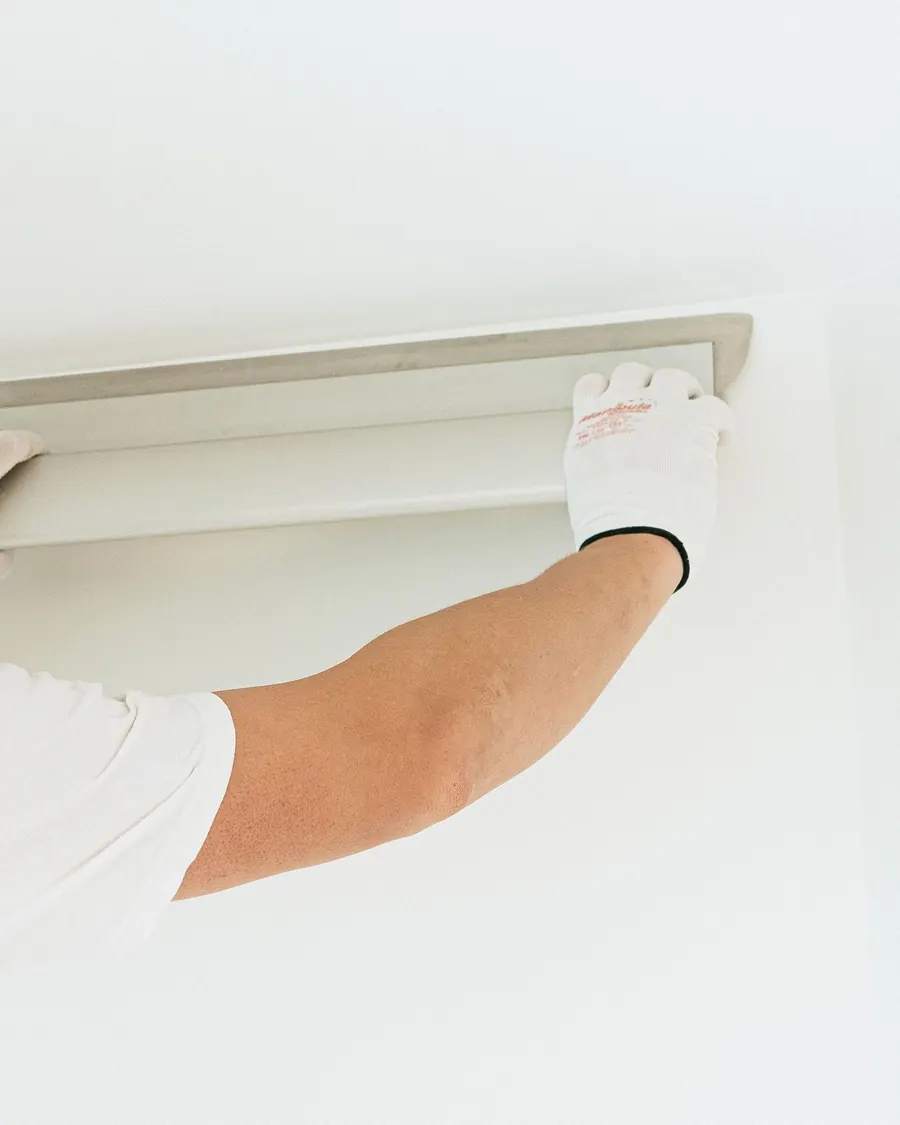 Installer mounting a device on a white ceiling